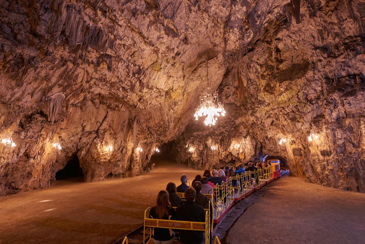 Turistički vlakić s posjetiteljima prolazi kroz osvijetljenu dvoranu Postojnske jame