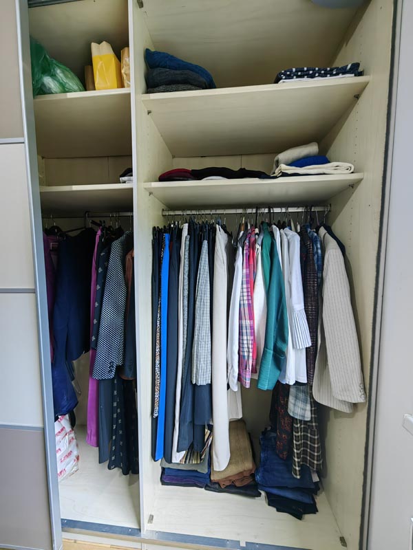organiziran-ugradbeni-ormar-slozena-odjeca Uredno organiziran ugradbeni ormar s odjećom na vješalicama razvrstanom po bojama, složenim hlačama na dnu i stvarima na gornjim policama.
