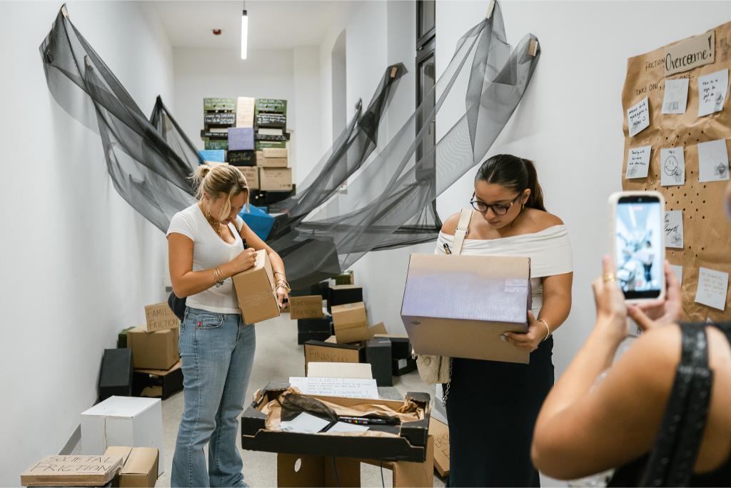 Posjetiteljice otvaraju kartonske kutije u sklopu interaktivne instalacije na Zagreb Design Weeku
