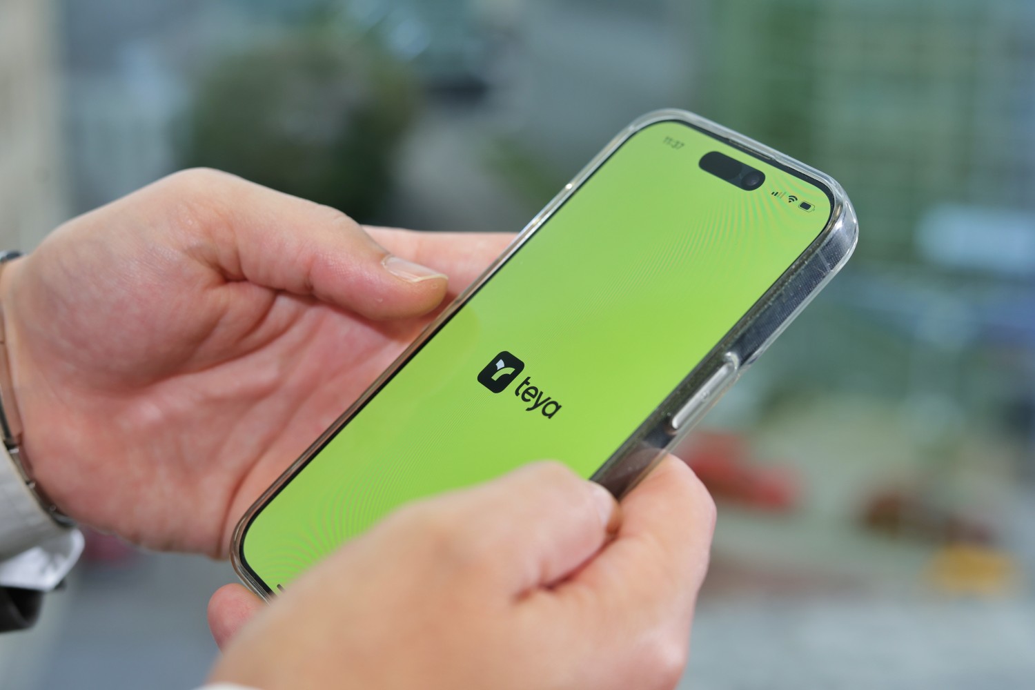 Ruke drže pametni telefon sa zelenim zaslonom i logotipom Teya aplikacije