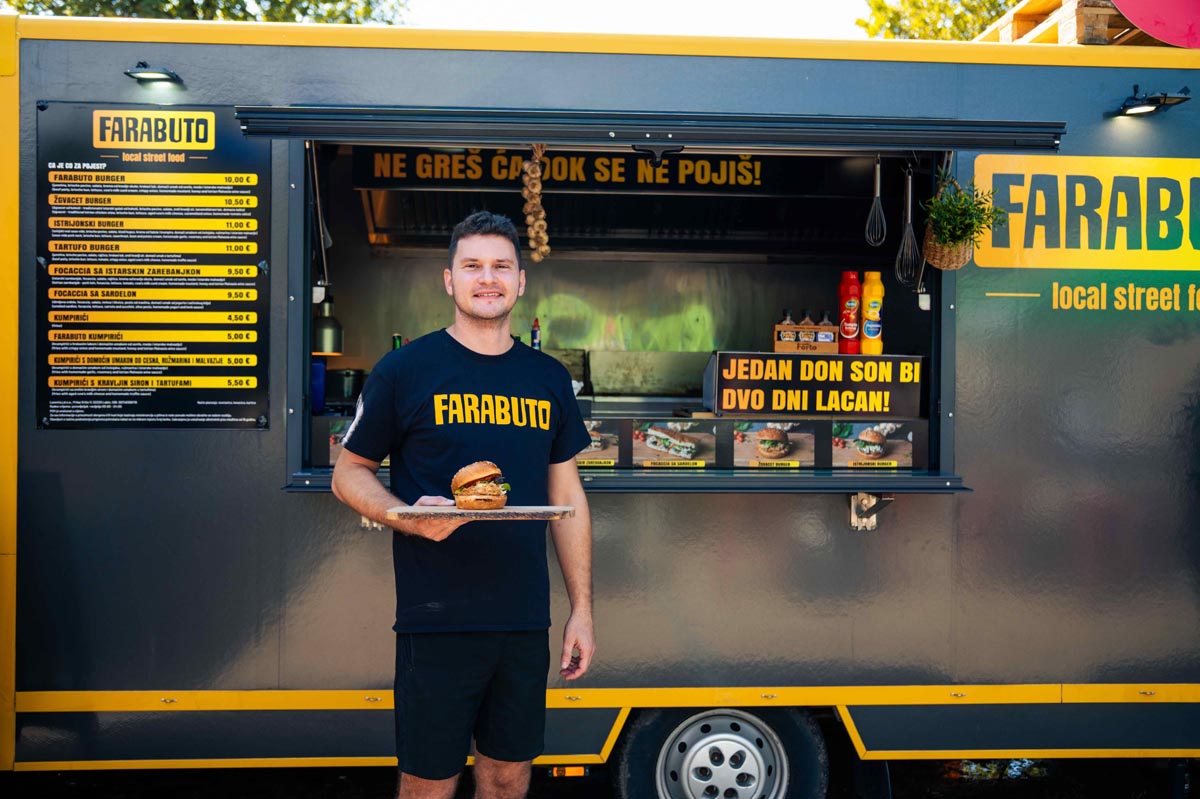 Toni Dragičević drži burger ispred žutog Farabuto street food kamiona