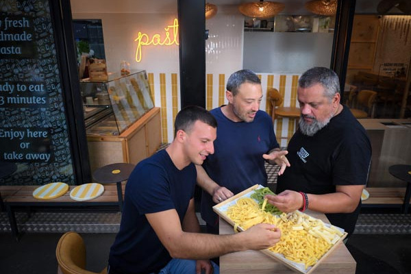 Kulinarski chefovi proučavaju pladanj s raznim vrstama svježe domaće tjestenine u restoranu.
