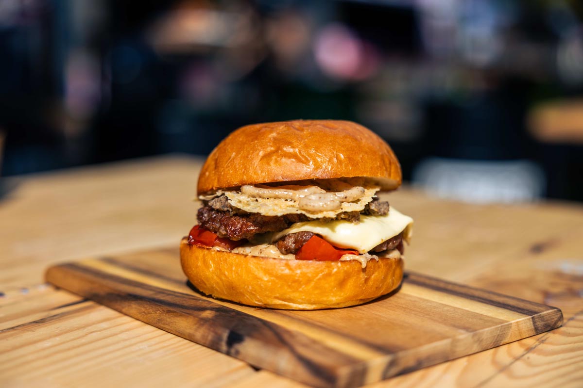 Burger s topljenim sirom, rajčicom i umakom na drvenoj dasci