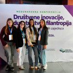 Četiri djevojke ispred plakata Društvene inovacije, poduzetništvo i filantropija