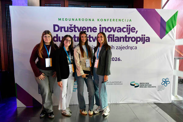 Četiri djevojke ispred plakata Društvene inovacije, poduzetništvo i filantropija
