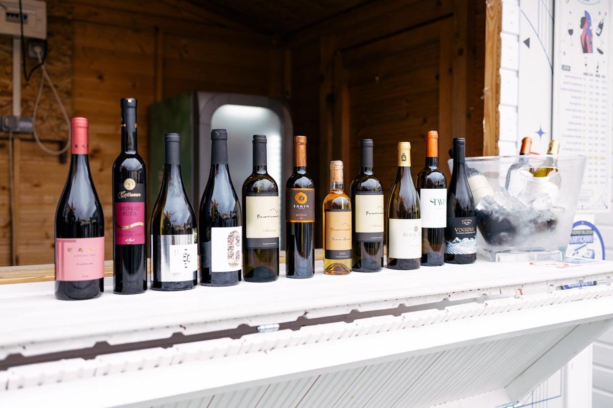 Različite sorte vina u bocama na bijelom šanku drvene kućice