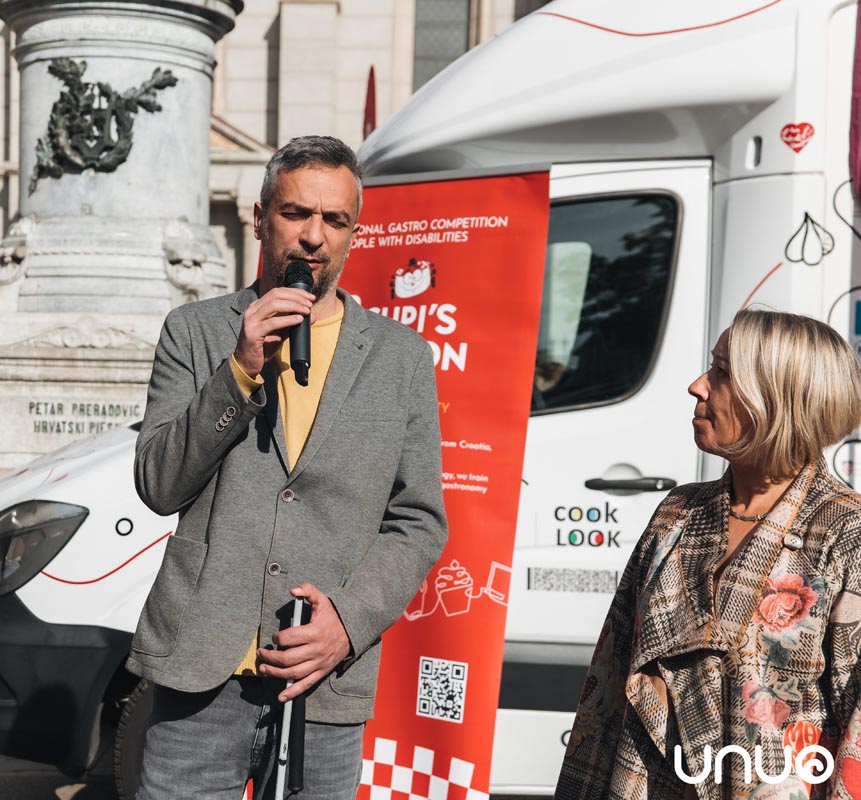 Govornik govori na mikrofon ispred Cupi's Spoon vozila udruge UNUO