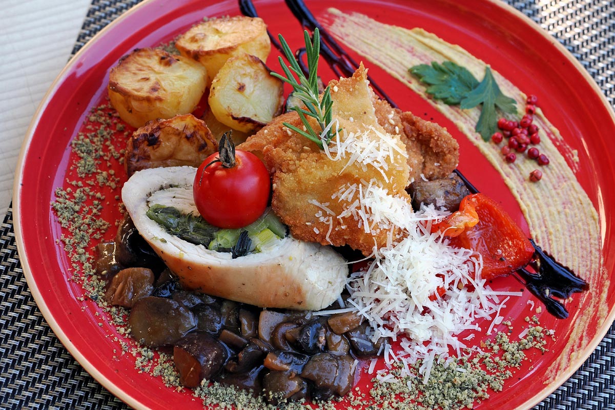 nedjeljni-rucak-kaiser-1 Kreativno glavno mesno jelo s pečenim krumpirom, umakom od gljiva i dekoracijom na crvenom tanjuru u à la carte Restoranu Kaiser.