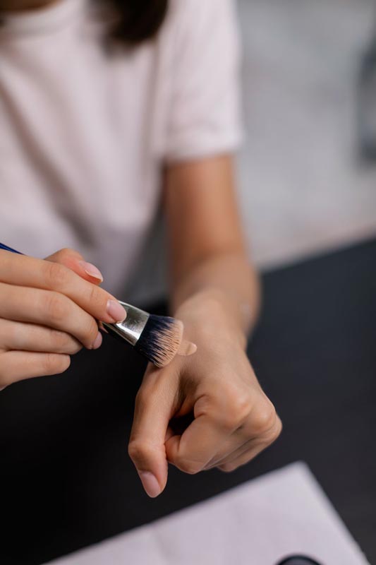 Testiranje tekućeg pudera na nadlanici pomoću plosnatog kozmetičkog kista