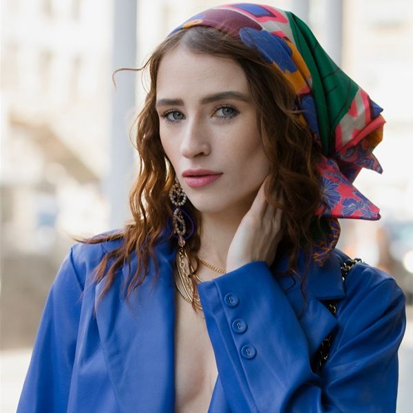 Šarena svilena marama na glavi u kombinaciji s upečatljivim plavim sakoom i nakitom