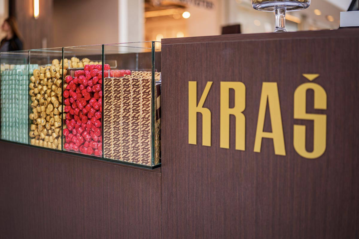 Prepoznatljivi Kraš logotip na pultu ekskluzivne trgovine s rinfuznim pralinama i slatkišima.