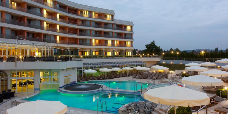 livada-hotel-moravske-toplice Vanjski bazeni i osvijetljena zgrada hotela Livada Prestige u Termama 3000 tijekom sumraka.