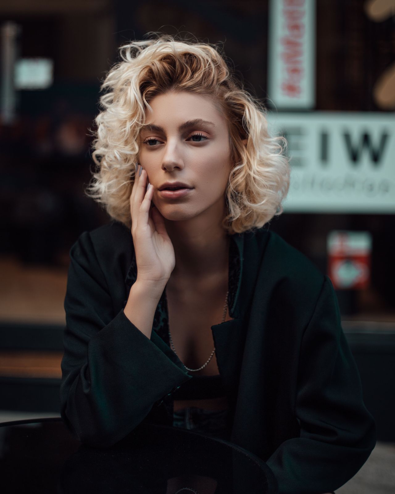 Portret plavokose žene u crnom sakou s urbanom pozadinom u zamućenju