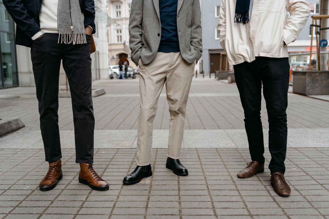 Tri muškarca u modernim casual kombinacijama i jesenskim cipelama na gradskoj ulici
