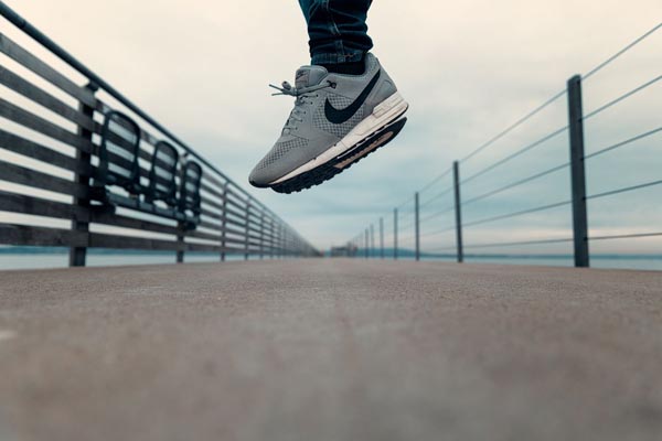 Sive Nike Air sportske tenisice u zraku tijekom skoka na modernoj šetnici.