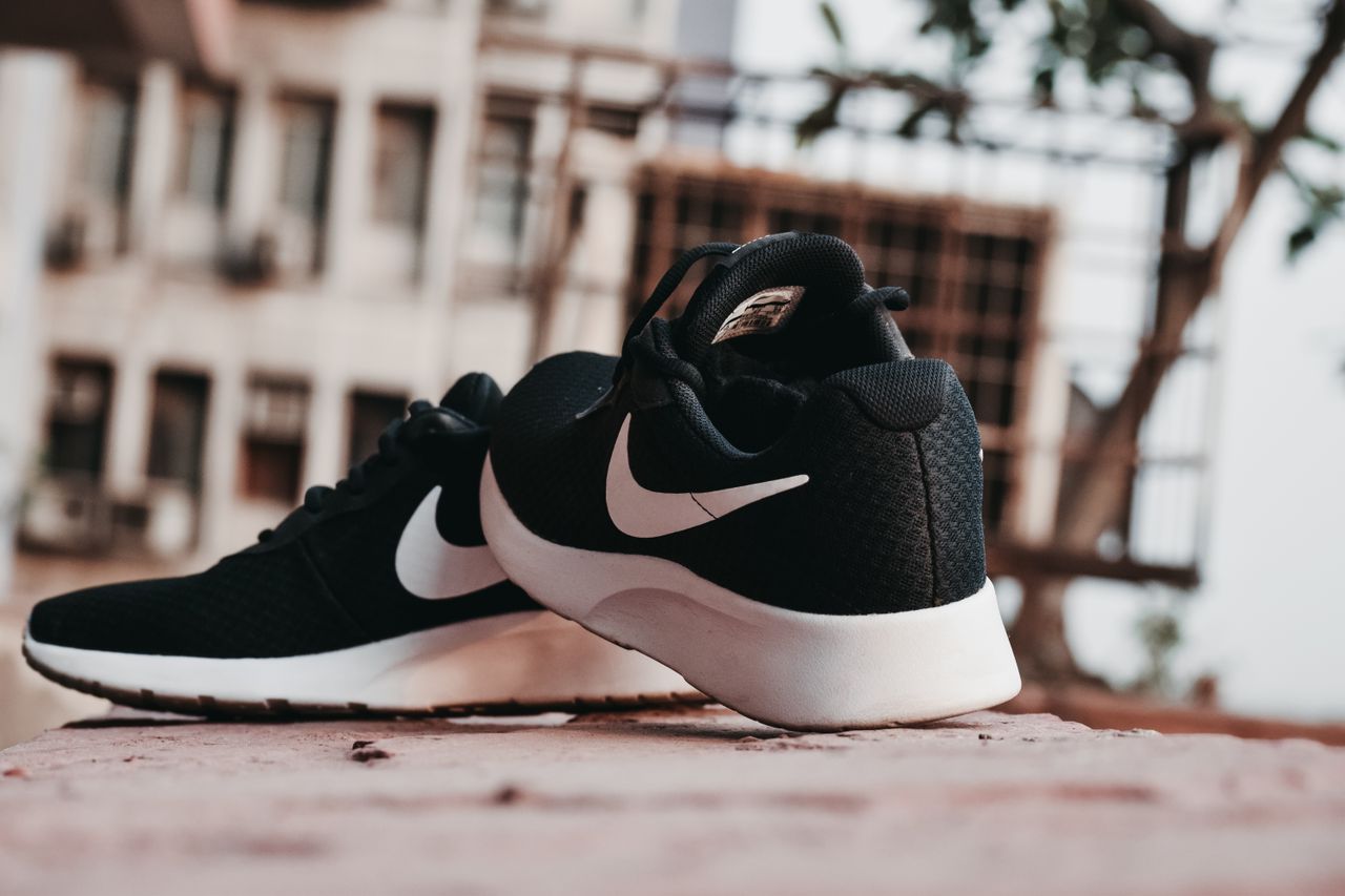 Crne sportske Nike tenisice s bijelim znakom na kamenoj podlozi na otvorenom.