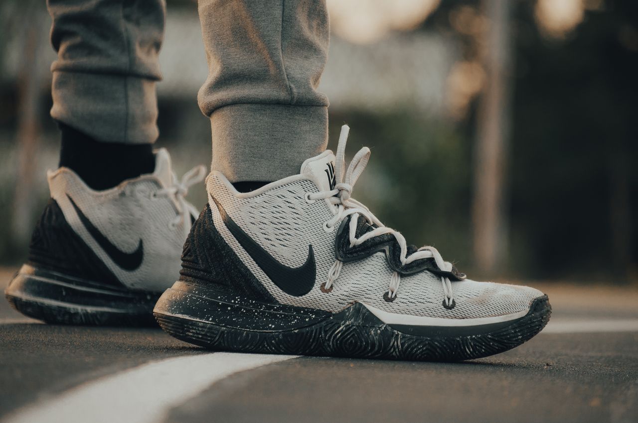 Visoke Nike Kyrie košarkaške tenisice u sivoj boji s crnim detaljima na sportskom terenu.