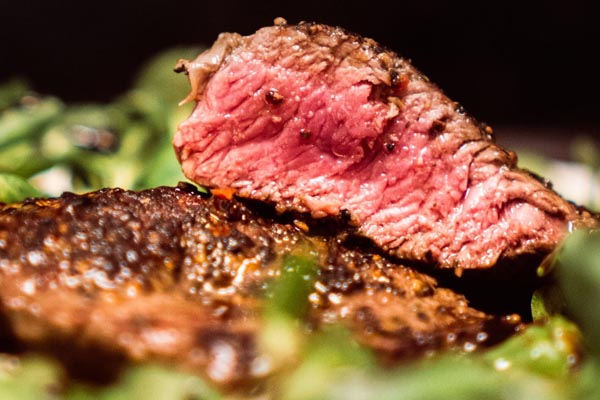 Krupni plan sočnog medium rare beefsteaka s zapečenom koricom, rezanog na kriške.