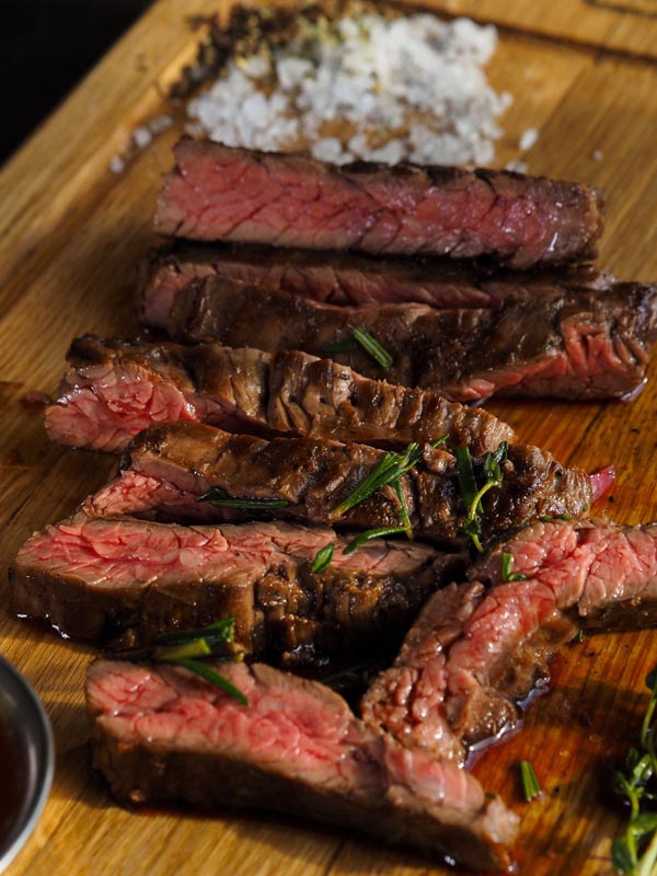 steak_u_restoranu_4 Narezani medium-rare goveđi odrezak poslužen na drvenoj daski s krupnom soli i svježim ružmarinom