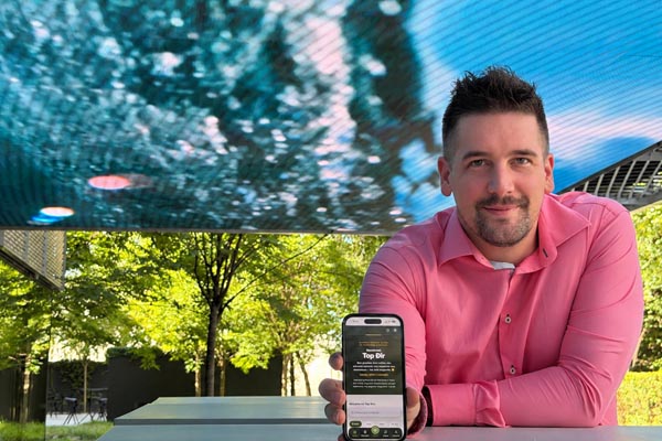 Suosnivač platforme Top Đir u ružičastoj košulji pokazuje mobilnu aplikaciju na ekranu mobitela