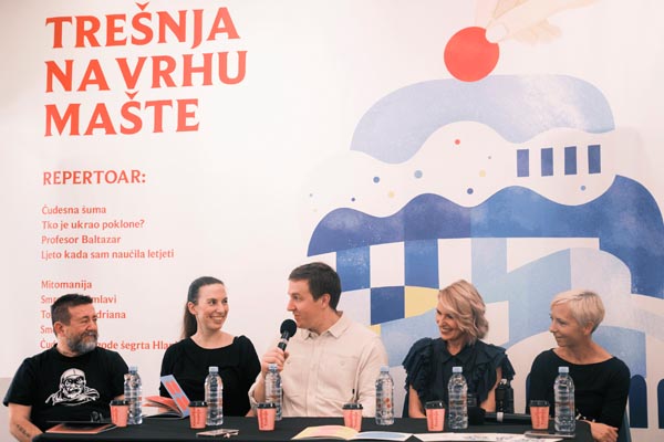 Sudionici panel rasprave govore na mikrofon ispred plakata Trešnja na vrhu mašte