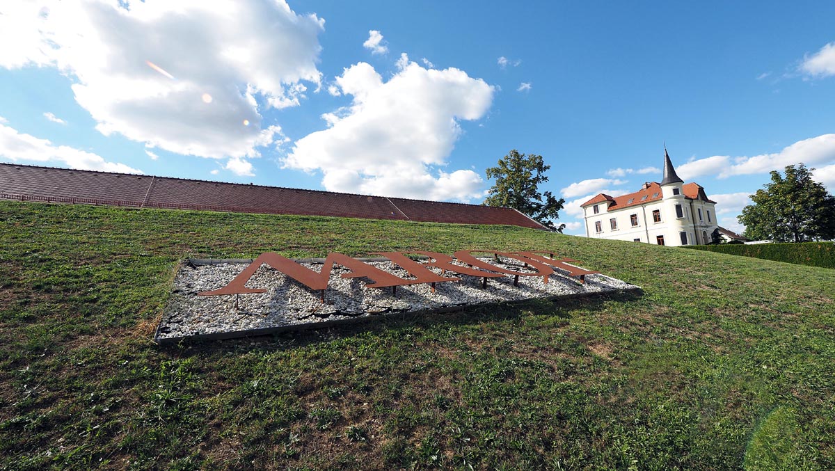 Veliki metalni natpis Marof na zelenoj padini ispred povijesnog dvorca Szápáry i plavog neba
