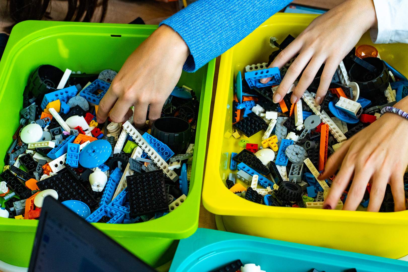 Ruke koje traže dijelove u plastičnim posudama punim šarenih kockica za robotiku na STEM radionici