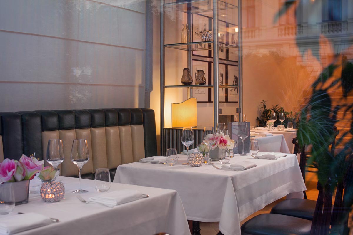 Elegantno postavljeni stolovi s cvjetnim dekoracijama i kristalnim čašama u restoranu Le Bistro Esplanade