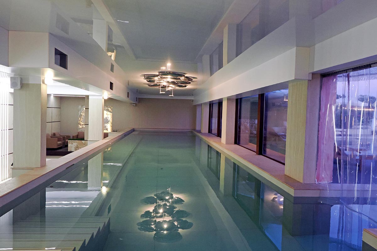 Dugački unutarnji bazen u spa zoni hotela Mantar s modernom rasvjetom i refleksijom na vodi