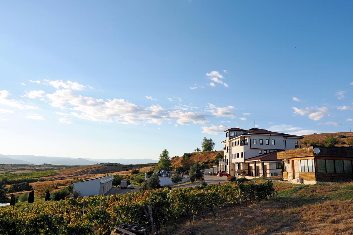 Moderna zgrada obiteljske vinarije Villa Melnik okružena zelenim brežuljcima i vinogradima u okolici Petriča