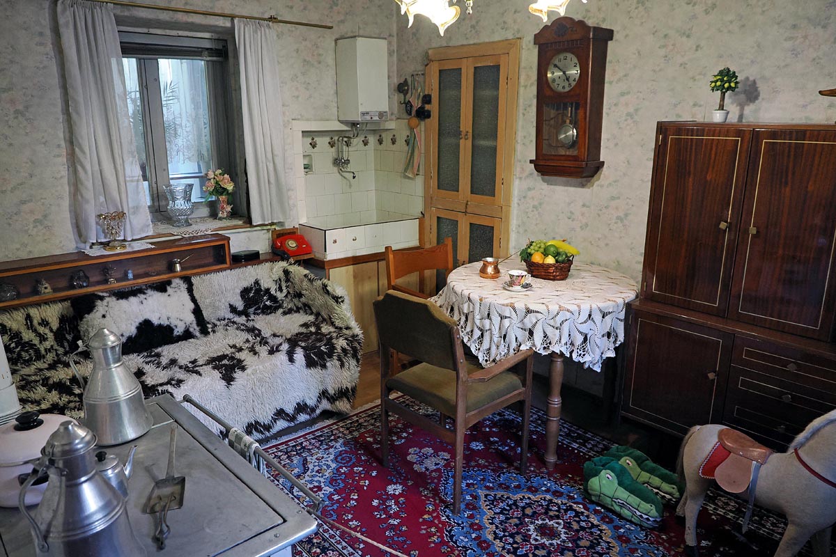 Tradicionalna dnevna soba Babe Vange u Petriču s okruglim stolom, starinskim satom i vunenim prekrivačem