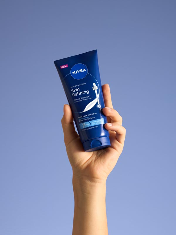 Ženska ruka drži plavu tubu Nivea Skin Refining serum losiona za intenzivnu hidrataciju kože