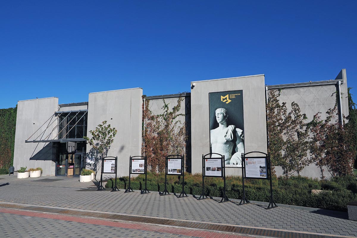 Moderna betonska zgrada Povijesnog muzeja u Petriču s reklamnim panoima i velikim plakatom antičke skulpture