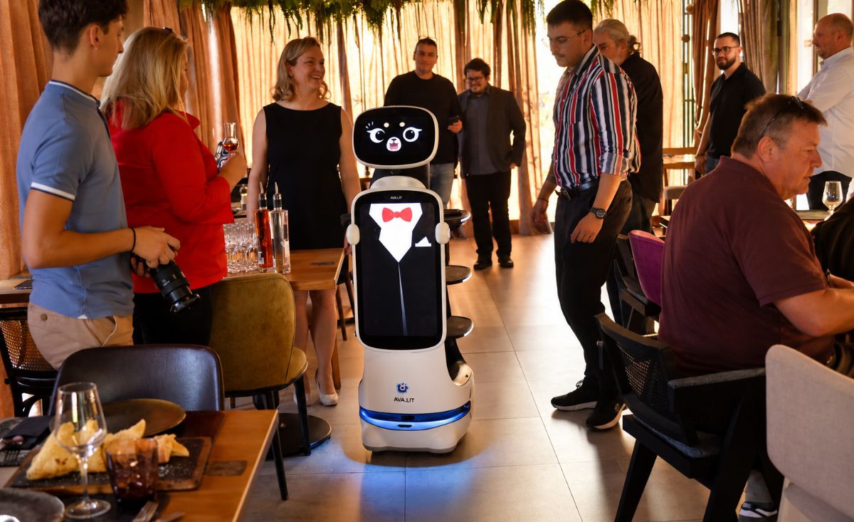 Robot konobar AVA.LIT s nacrtanim smokingom kreće se kroz salu pizzerije Mrs. Fogg među okupljenim gostima