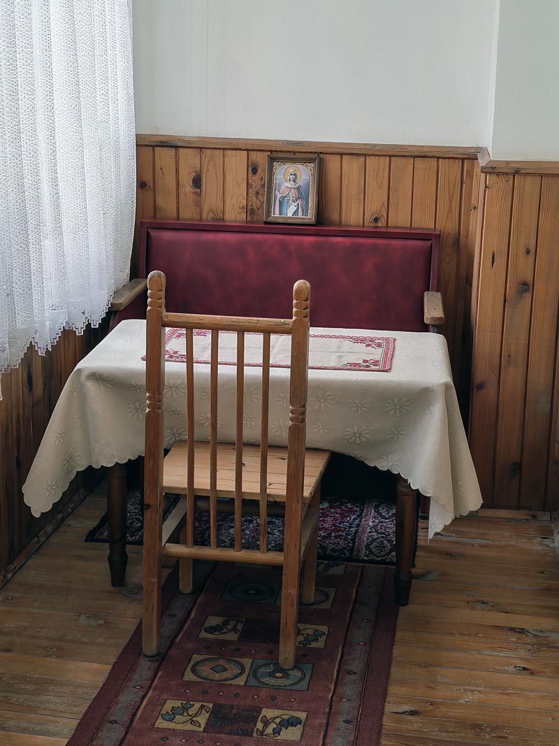 Drveni stol i stolica s malom ikonom na zidu u kući Baba Vange u Rupitama