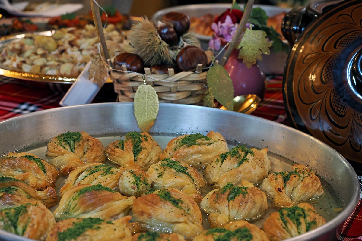 Domaća baklava s pistacijama u tepsiji s košarom divljih kestena u pozadini