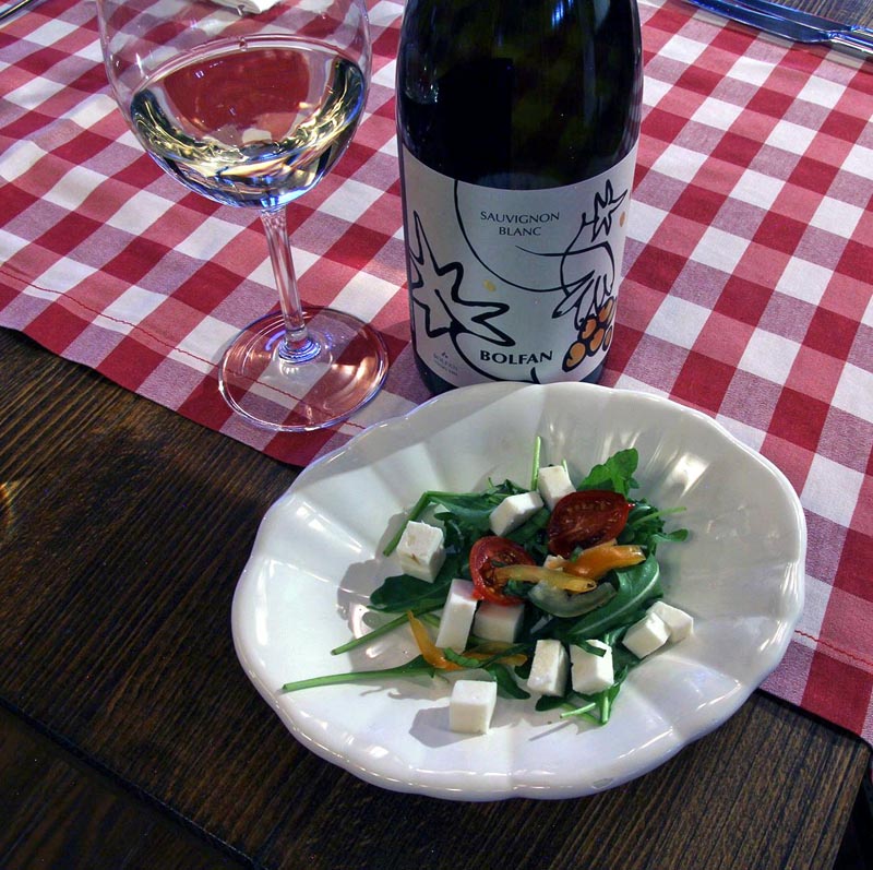 Boca Bolfan Sauvignon Blanc vina, čaša i tanjur sa salatom i kockicama sira na stolnjaku