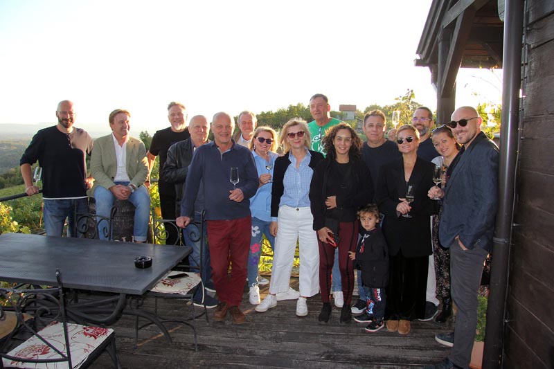 Grupa ljudi s čašama pozira na drvenoj terasi vinarije Bolfan s pogledom na vinograd