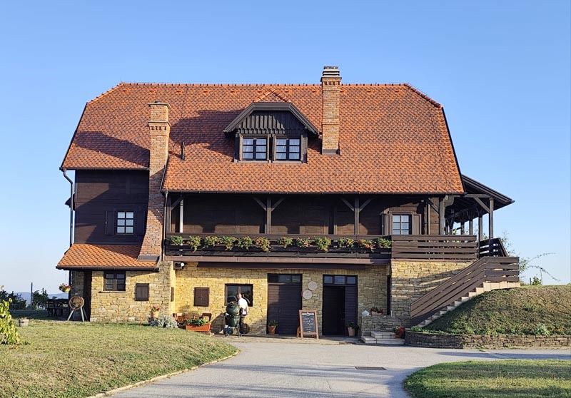 Kamena i drvena kuća vinarije Bolfan Vinski Vrh pod plavim nebom