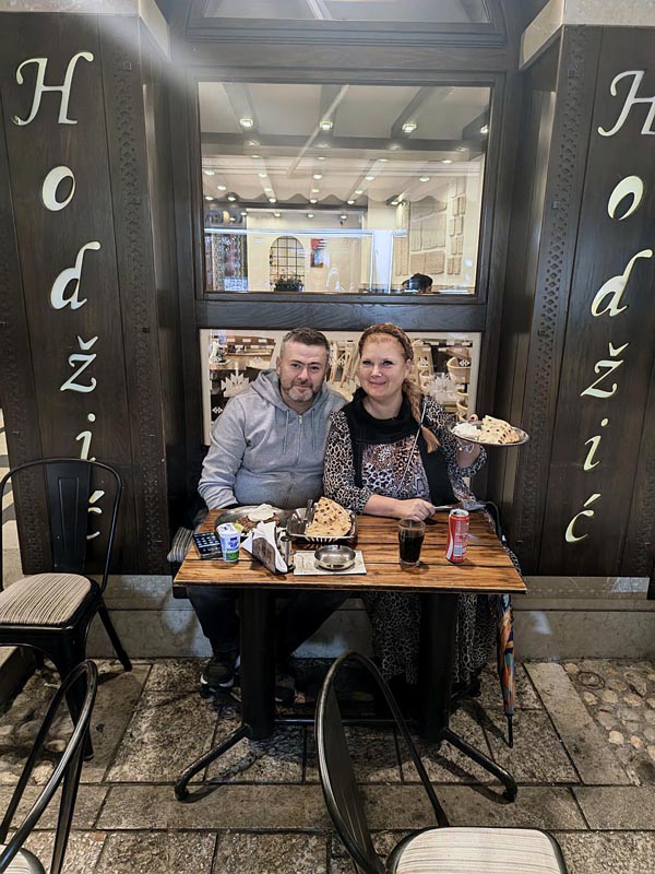 Nikola i Alma sjede za stolom ispred ćevabdžinice Hodžić na Baščaršiji u Sarajevu