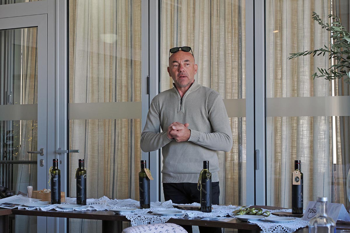 Branko Karabaić predstavlja vrhunsko maslinovo ulje OPG Rošulja pored izloženih boca na stolu
