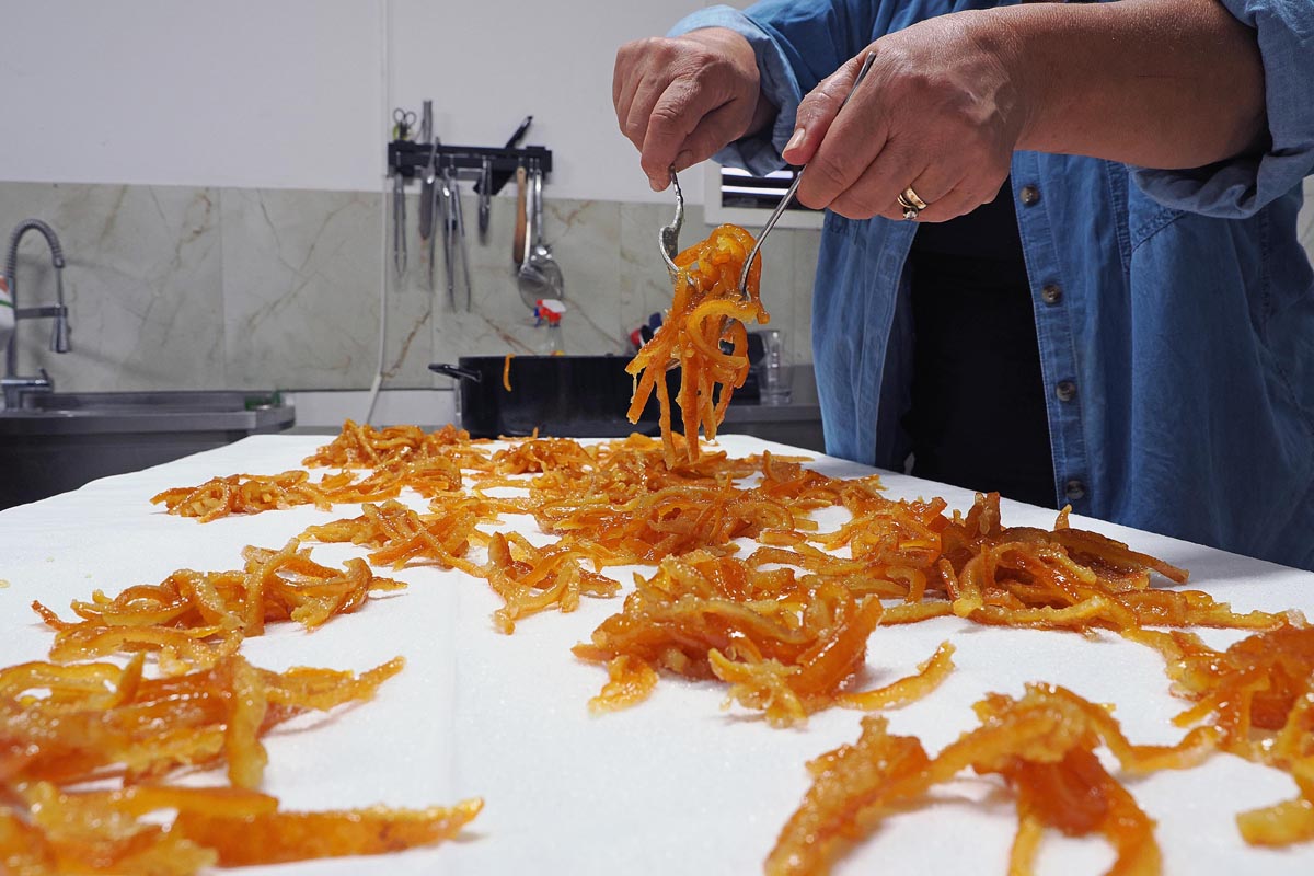 Krupni kadar raspoređivanja kandiranih kora od mandarine na stolu u proizvodnji tradicionalnih arancina