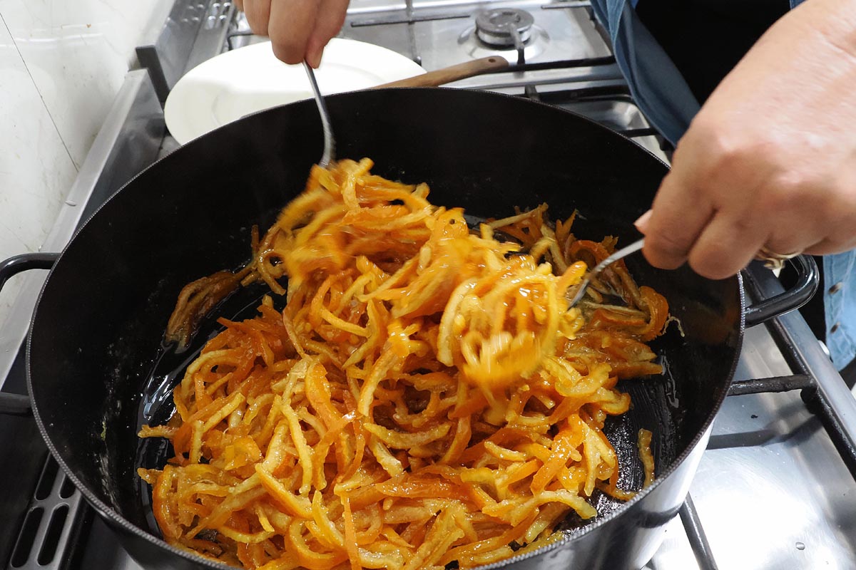 Kuhanje narezane kore od mandarin u velikom crnom loncu na štednjaku za pripremu arancina