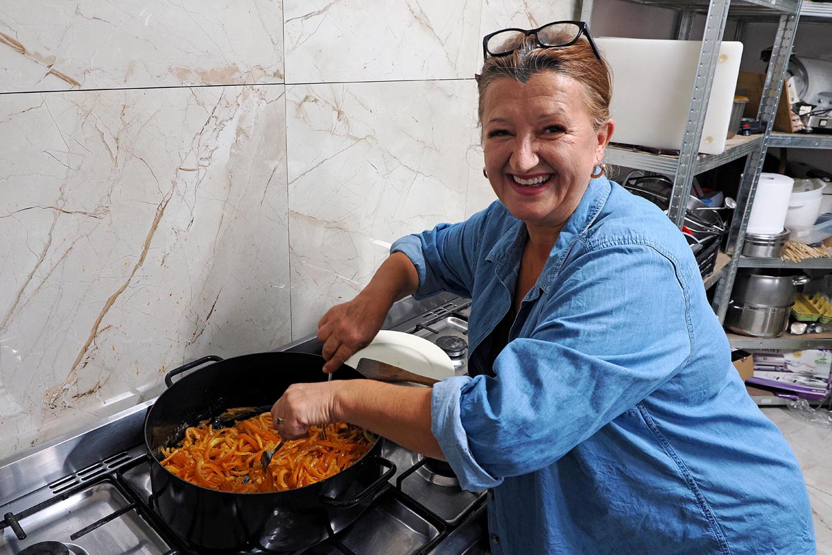 Nasmijana Branka Pratežina kuha koru mandarine u velikom crnom loncu u kuhinji OPG-a Dvi ribe dva kumpira