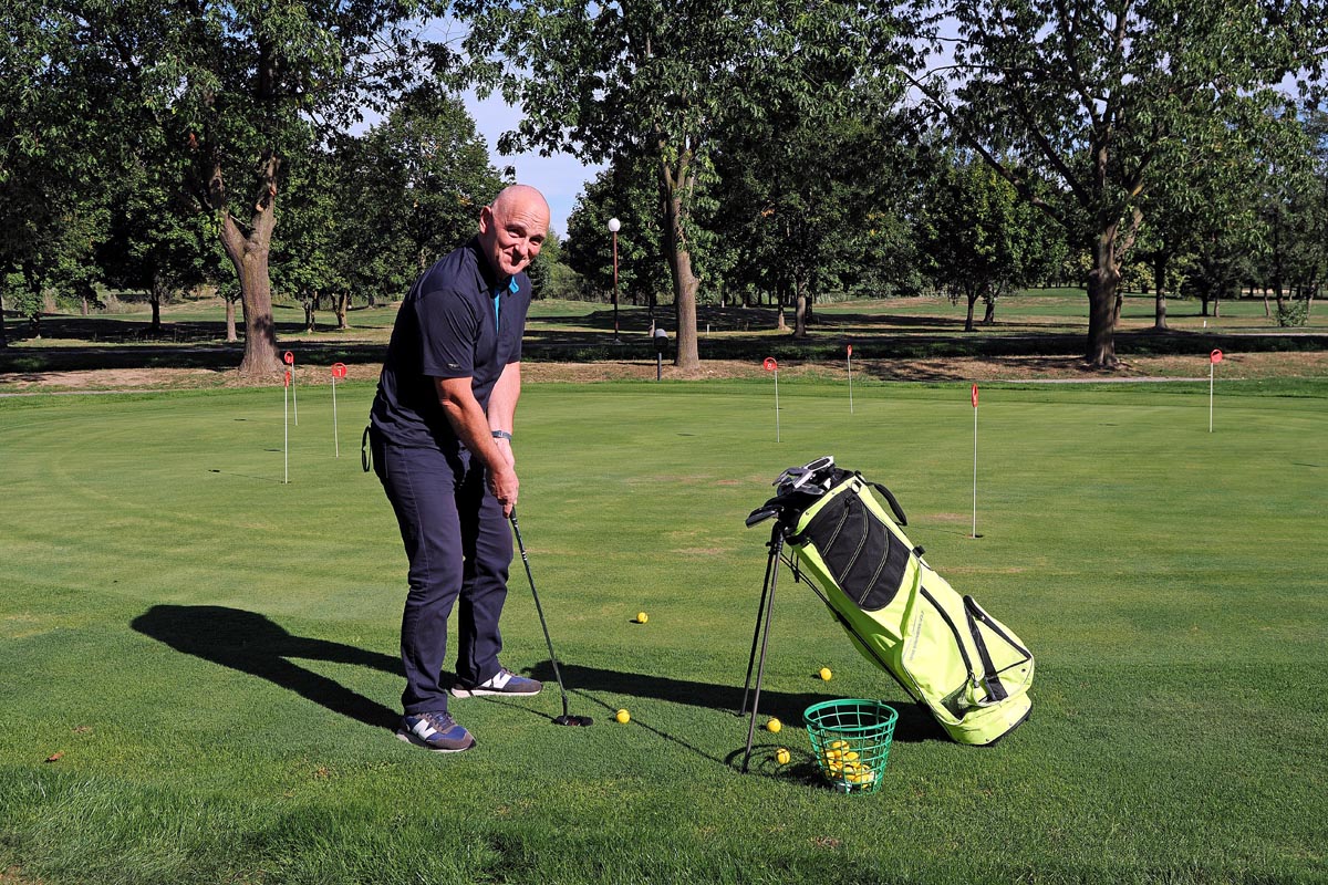 Daniel Donša vježba udarac na golf terenu uz torbu s palicama i žute loptice