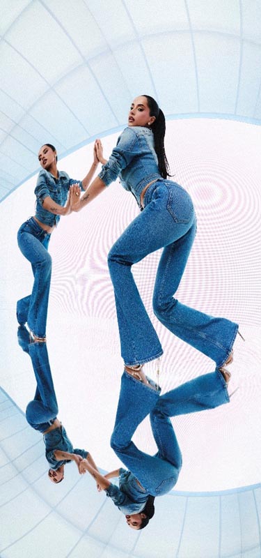 Becky G u Guess trapericama u obliku zvona i traper jakni pozira na zrcalnoj površini s odrazom