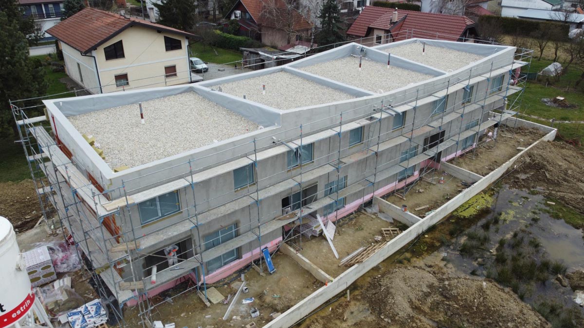 Moderna zgrada u izgradnji s postavljenom građevinskom skelom i ravnim šljunčanim krovom