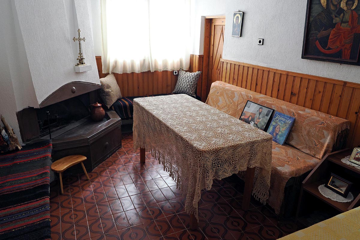 Unutrašnjost kuće Baba Vange u Rupitama sa stolom prekrivenim čipkastim stolnjakom i kaminom
