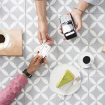 Plaćanje Mastercard karticom preko POS terminala u kafiću uz šalicu kave, komad kolača i vrećicu kave