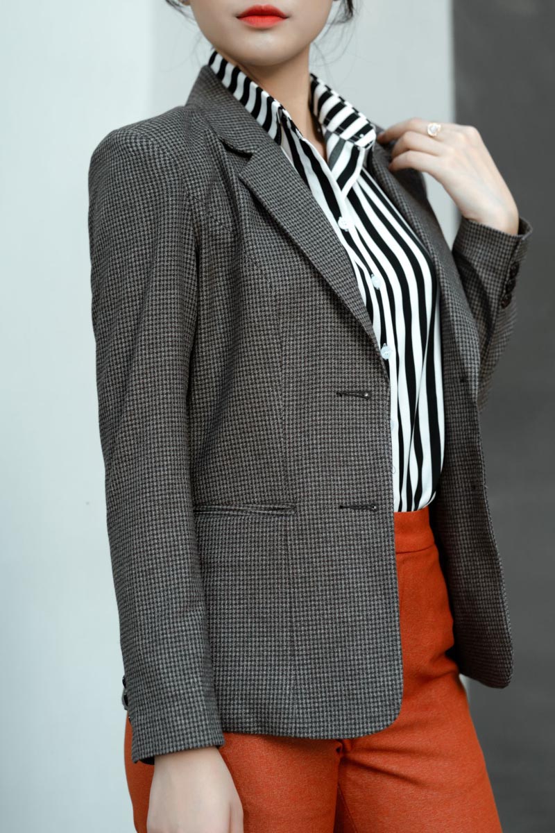 Model u tamnosmeđem pepita sakou, crno-bijeloj prugastoj košulji i upečatljivim narančastim hlačama
